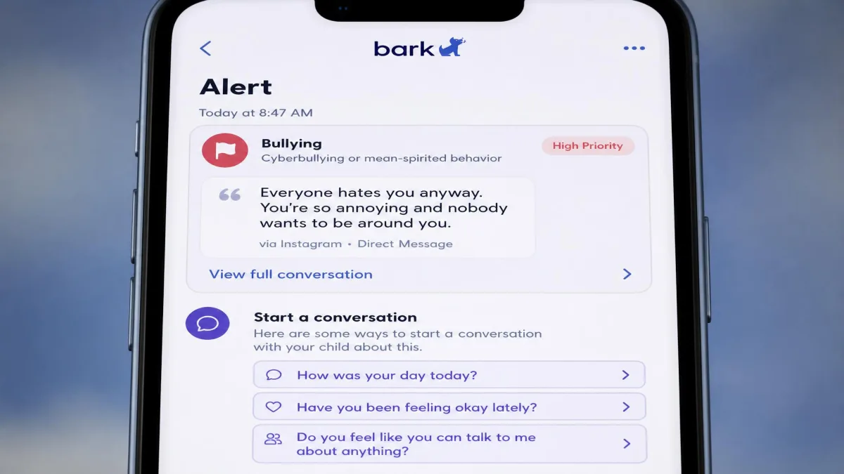 Close-up of Bark's alert detail screen on a phone, showing a flagged message excerpt categorised as bullying with suggested conversation prompts underneath.