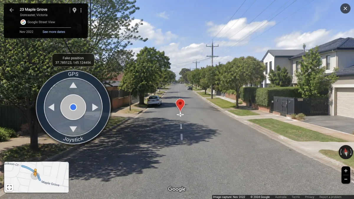 The GPS JoyStick circular overlay control floating over a Google Maps street view, with the fake position marker part way along a residential road.