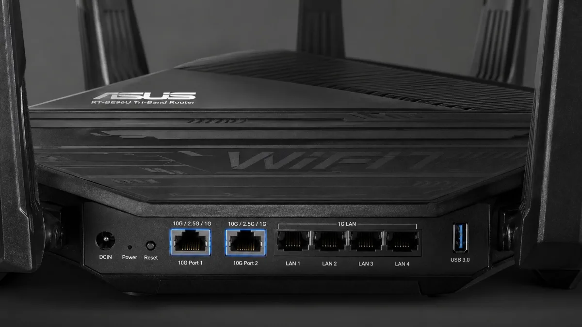 Close-up of the Asus RT-BE96U rear panel showing two 10 Gbps multi-gig ports and four gigabit LAN ports, with the tall tri-band chassis behind.