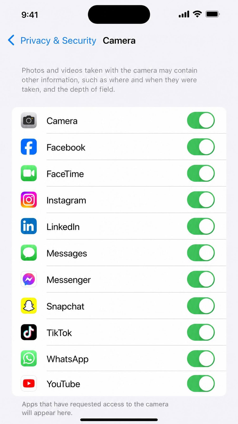 The iPhone Settings screen at Privacy & Security then Camera, showing a list of apps with green toggle switches controlling camera access.