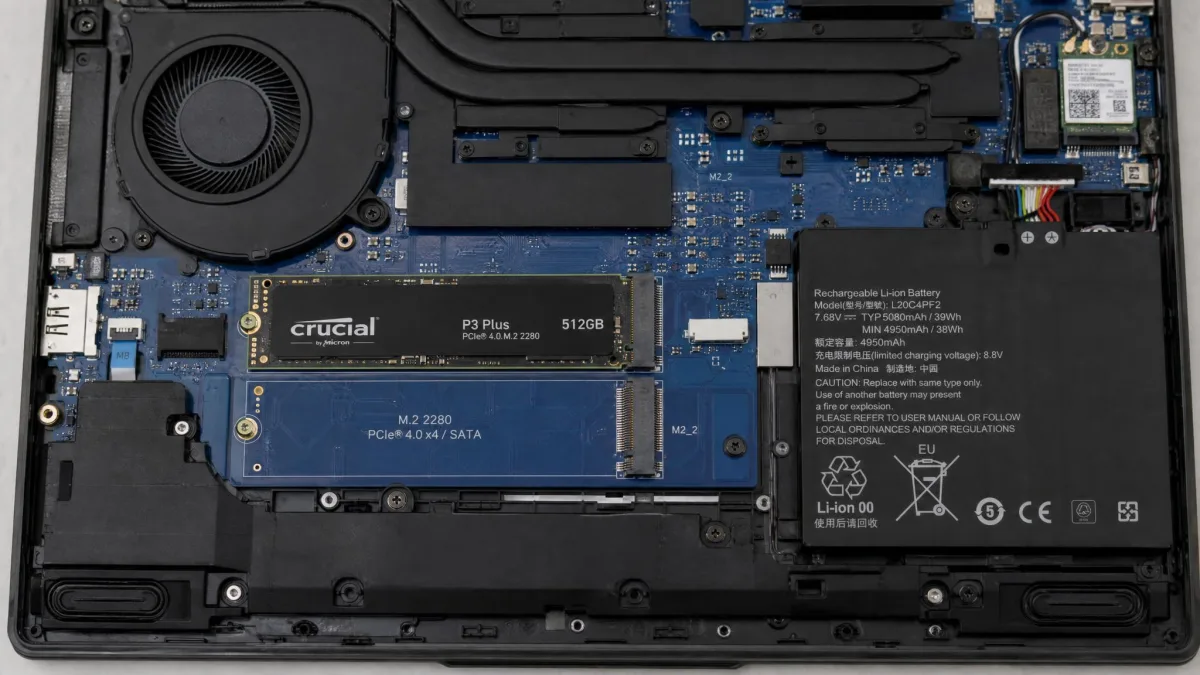 The underside of an open laptop with the bottom panel removed, showing a 512 GB M.2 SSD seated in the primary slot and an empty secondary M.2 slot beside it.