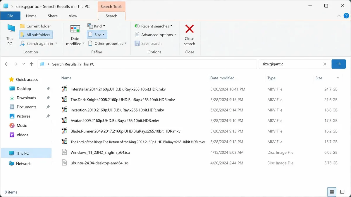 File Explorer search results on This PC filtered by size:gigantic, sorted by Size, showing several multi-gigabyte video and ISO files.