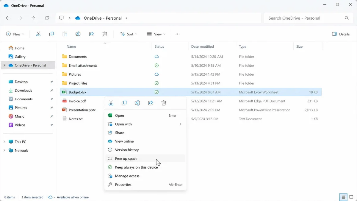 File Explorer OneDrive folder with the right-click menu open on Free up space, and cloud and green tick status icons in the Status column.
