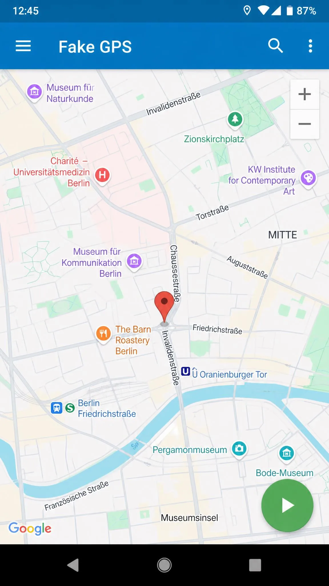 The Fake GPS location app open on an Android phone with the map centred on a European city, a pin dropped on a street corner, and the green play button ready to start the mock location.