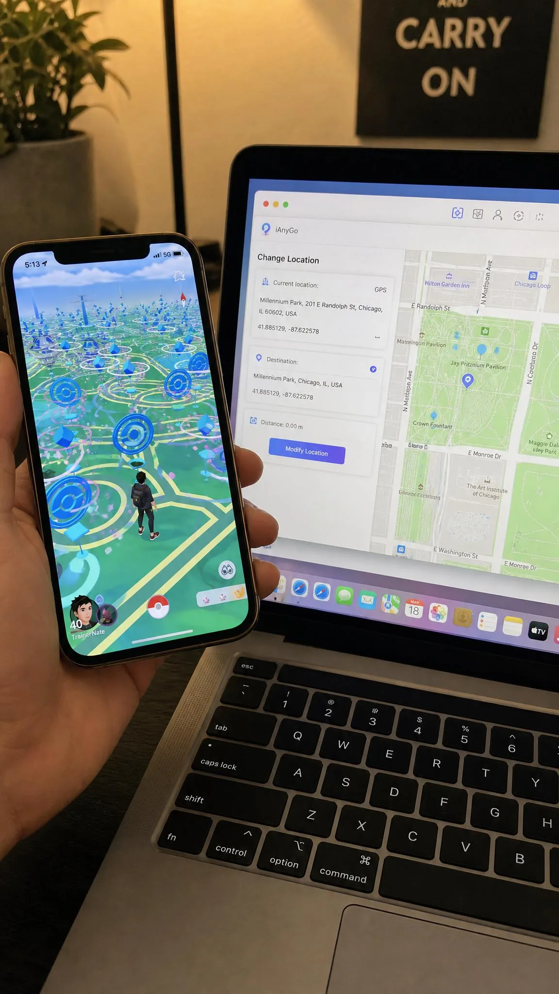 An iPhone showing the Pokemon GO map screen with the avatar standing in a dense downtown park full of PokeStops, held next to a laptop running a desktop location changer.
