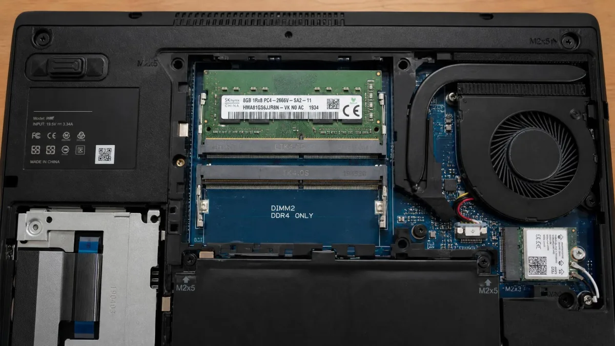 The underside of an open laptop with the bottom panel removed, showing two memory slots with one occupied by an 8 GB module and the second slot empty.