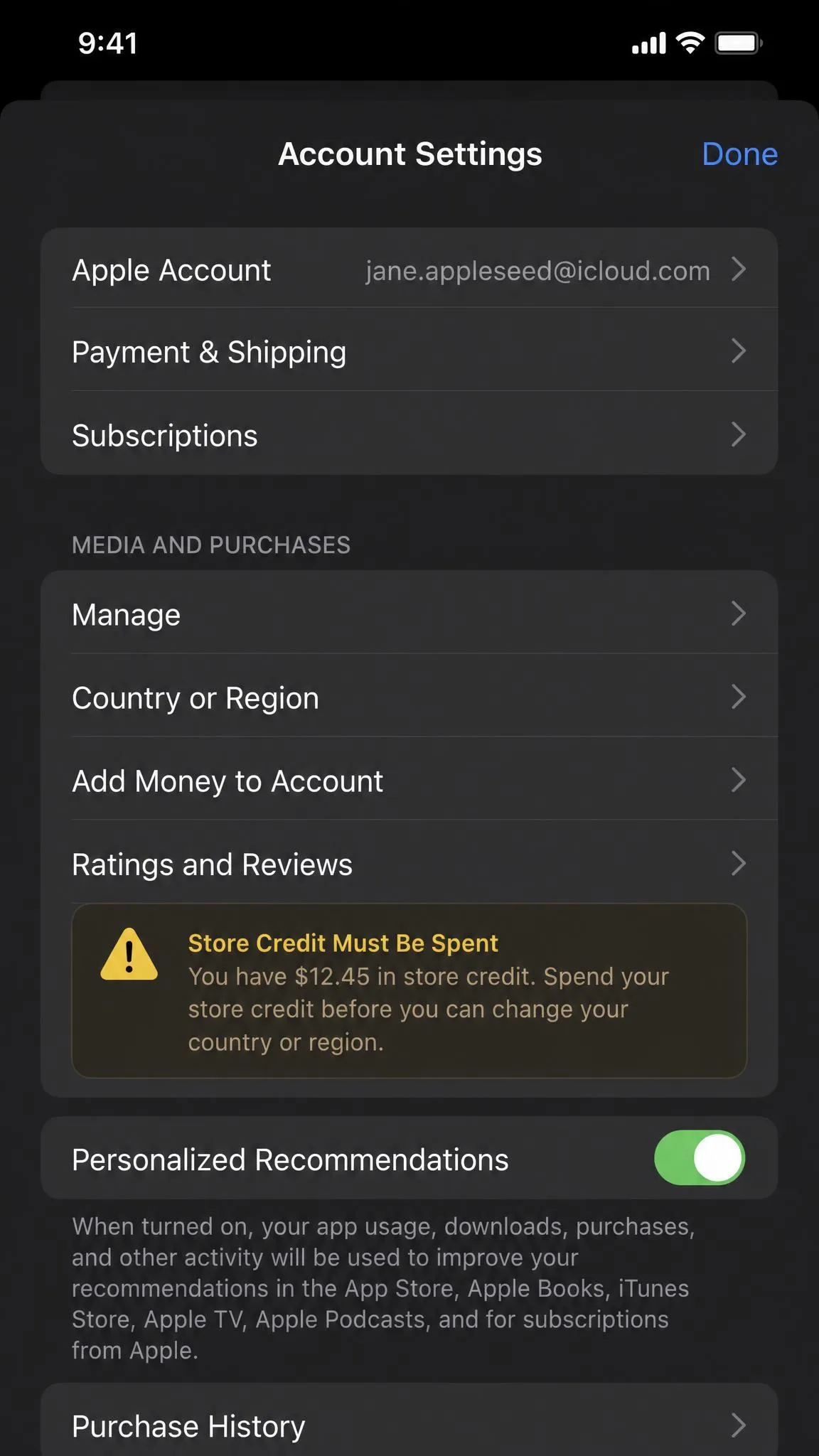 An iPhone account settings screen showing the Country or Region row under Media and Purchases, with a warning about store credit needing to be spent before the region can be changed.