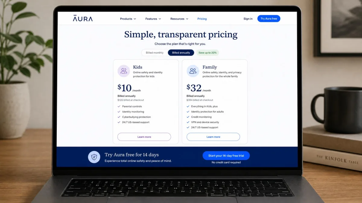 Aura's pricing page shown on a laptop with the Kids plan at ten dollars per month billed annually beside the Family plan at thirty-two dollars per month, with the fourteen-day free trial button highlighted.