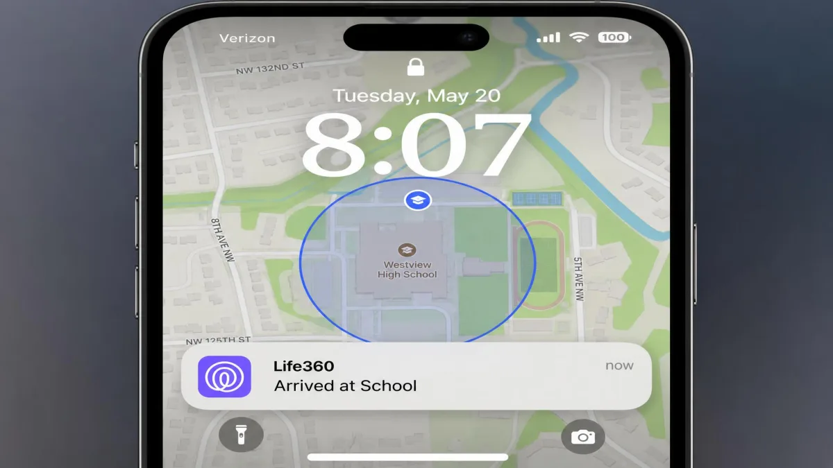 A phone lock screen showing a Life360 notification reading Arrived at School, with the Life360 map visible behind it and a blue geofence circle drawn around a school building.