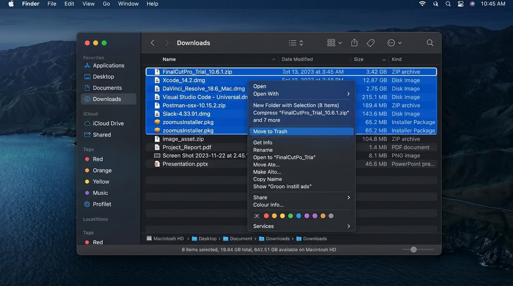 A Finder window open to the Downloads folder in list view, sorted by size, with several .dmg installer files and zip archives selected for deletion.